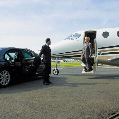 man coming out of the airplane while driver standing near the car