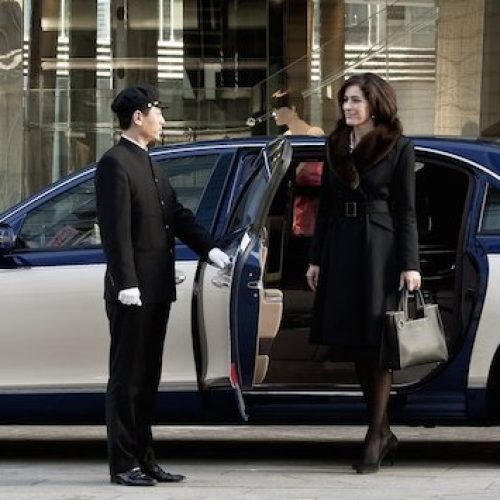 driver holding car door while women coming out of the car